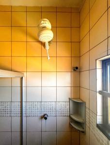 ein gelb gefliestes Bad mit einer Dusche und einer Lampe in der Unterkunft Kitnet beira mar com WiFi em Arembepe Camacari BA in Camaçari