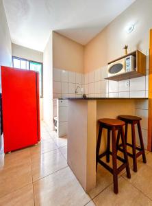 eine Küche mit zwei Hockern und einem roten Kühlschrank in der Unterkunft Kitnet beira mar com WiFi em Arembepe Camacari BA in Camaçari