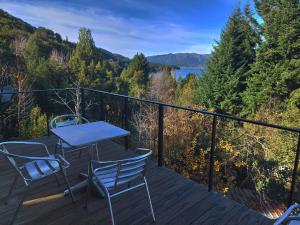 een tafel en stoelen op een terras met uitzicht op een meer bij Tres Vistas in Bariloche