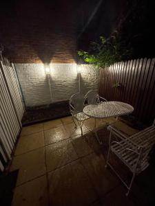 una mesa y sillas en un patio por la noche en Victorian Refuge-City centre-3bedroom house, en Canterbury