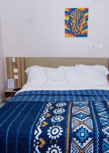 a bed with a blue and white blanket on it at BUNGALOW'S PLAZA KRIBI in Kribi