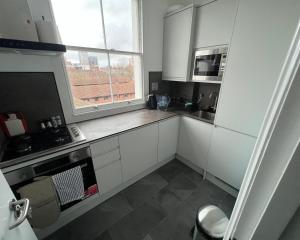 eine kleine Küche mit weißen Schränken und einem Fenster in der Unterkunft 2 Bed Apartment in Central London on 3rd floor - Newly refurbished - No lift in London