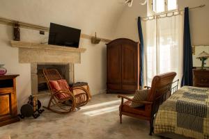 1 dormitorio con chimenea, 2 sillas y TV en Masseria Dimora del viandante - by Click Salento en Sogliano Cavour