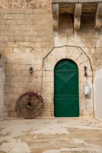 una puerta verde junto a una pared de ladrillo con una rueda en Masseria Dimora del viandante - by Click Salento en Sogliano Cavour