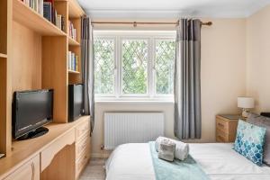 een slaapkamer met een bed, een tv en een raam bij Ross House in Black Notley