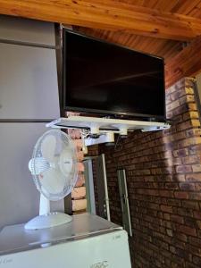 a flat screen tv above a refrigerator with a fan at Belle Vue Guesthouse in Hartbeespoort