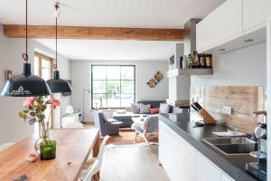 eine Küche und ein Wohnzimmer mit weißen Schränken und einem Tisch in der Unterkunft Das Alpbach Tegernsee - Design Suites in Tegernsee