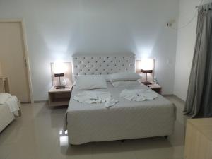 een slaapkamer met een groot bed met twee lampen aan beide zijden bij Lisboa Palace Hotel in Alta Floresta