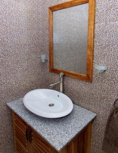 a bathroom with a white sink and a mirror at BUNGALOW'S PLAZA KRIBI in Kribi