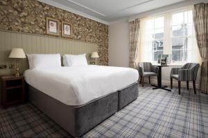a hotel room with a large bed and a desk at The Ullswater Inn- The Inn Collection Group in Glenridding