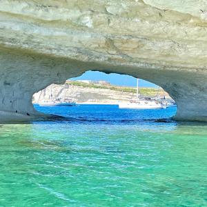a boat sitting in the water under a stone cave at Tan-Nanniet Two Bedroom Apartment in Marsaxlokk