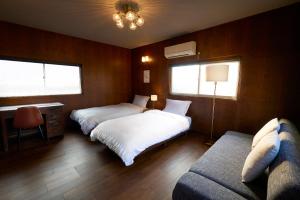 a bedroom with two beds and a couch and windows at 結家 -MUSUBIYA- in Kawagoe