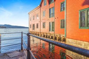 un edificio naranja junto a un cuerpo de agua en Ocean-view Haven: Take a swim from your window!, en Bergen 8 fotos más