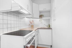 Una cocina blanca con gabinetes blancos y un fregadero. en Ocean-view Haven: Take a swim from your window!, en Bergen