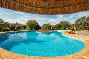 uma grande piscina com piso de madeira e um guarda-sol de madeira em Country chic duplex in Algarve em Pêra