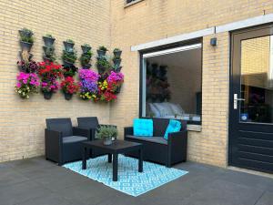 a patio with two chairs and a table and flowers at Studio 23 in Zandvoort