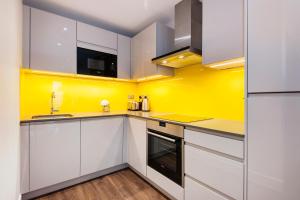 una cocina con armarios blancos y una pared amarilla en Twyne House Apartments en Londres