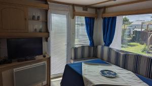 a small room with a television and a table with a plate on it at Mobil home avec terrasse camping du gouffre numéro 88 plougrescant in Plougrescant