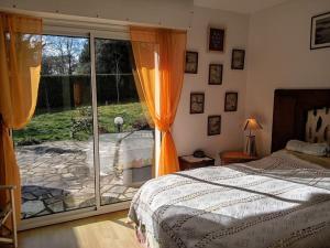 a bedroom with a bed and a sliding glass door at Ty Clafout Vannetaise in Saint-Nolff