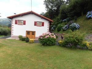 een klein wit huis met bloemen op een heuvel bij 3 bedrooms house at Larrapil Sarriku in Etxalar