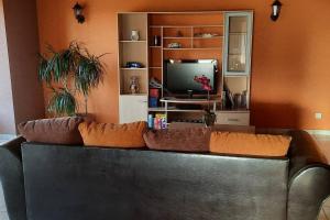 ein schwarzes Ledersofa im Wohnzimmer mit TV in der Unterkunft Villa de 3 chambres avec terrasse et wifi a Saint Georges de Baroille in Saint-Georges-de-Baroille