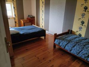 1 Schlafzimmer mit 2 Betten und Holzboden in der Unterkunft Villa de 3 chambres avec terrasse et wifi a Saint Georges de Baroille in Saint-Georges-de-Baroille