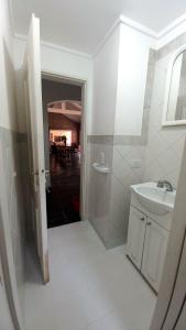 La salle de bains blanche est pourvue d'un lavabo et d'un miroir. dans l'établissement CASA BARRIO CERRADO EN LUJAN LA CONCEPCION, à Luján