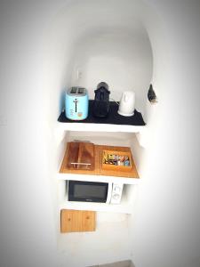 una pequeña cocina con microondas en un estante en EL PATRON SANTORINI en Fira