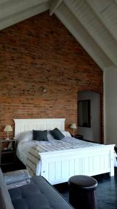 - un lit blanc dans une chambre dotée d'un mur en briques dans l'établissement CASA BARRIO CERRADO EN LUJAN LA CONCEPCION, à Luján