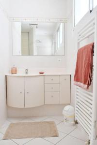 een witte badkamer met een wastafel en een spiegel bij Maison à 6 km de Eymet piscine chauffée. in Roumagne