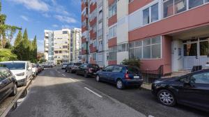 a row of cars parked on a street next to buildings at Sunny Horizon Retreat by LovelyStay in Paço de Arcos