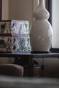 Santé Wellness Retreat & Spa في بارل: وجود مزهرية بيضاء على طاولة بجانب صندوق