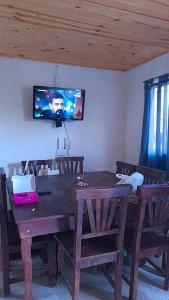 einen Holztisch mit Stühlen und einen TV an der Wand in der Unterkunft Casa en Boca del Río in Las Tapias