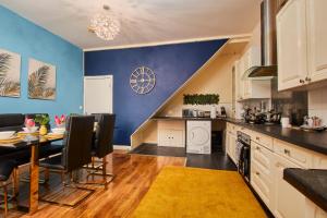 a kitchen with a table and a blue wall at Sleek House - 5 Minutes From Newcastle City Centre in Newcastle upon Tyne