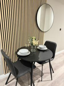 a black table with two chairs and a mirror at Flat 61 Serenity Apartment in Beeston Hill