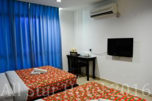 een kamer met 2 bedden, een bureau en een televisie bij HP Rooms All Star Hotel in Melaka