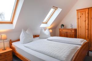 1 dormitorio con 1 cama con sábanas blancas y 2 ventanas en Villa Zur Alten Post, en Kühlungsborn 8 fotos más