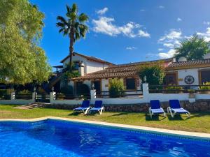 a villa with a swimming pool in front of a house at La Granja de Antonio in Alhaurín el Grande