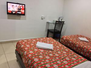 een kamer met 2 bedden en een tv aan de muur bij HP Rooms All Star Hotel in Melaka