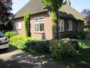 una casa con un árbol y flores delante de ella en B&B Loon, en Loon