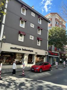 um carro vermelho estacionado em frente a um grande edifício em Emsa Otel Maltepedeki Eviniz em Istambul