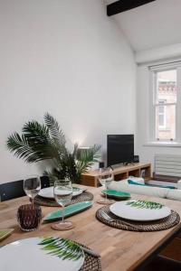 a wooden table with plates and wine glasses on it at City Superhost - Northern Quarter Loft Conversion in Manchester +19 photos
