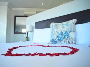 Atlantic Oasis Guest House في تابل فيو: سرير عليه قلب مصنوع من الورود