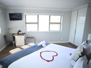 Atlantic Oasis Guest House في تابل فيو: غرفة نوم بسرير كبير عليها وردة حمراء