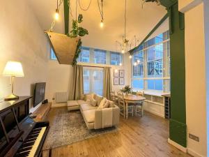 a living room with a couch and a piano at City Centre Loft Apartment in Stalybridge