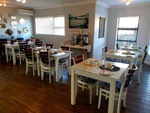 Atlantic Oasis Guest House في تابل فيو: غرفة طعام مع طاولات وكراسي بيضاء