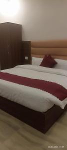 Butola Hotels في ريشيكيش: غرفة نوم بسرير كبير مع شراشف حمراء وبيضاء