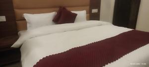 a large bed with white sheets and red pillows at Butola Hotels in Rishīkesh