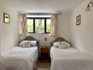 Dos camas individuales en una habitación con ventana. en Lake Villa Holiday Cottages, en Holsworthy
