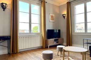 a living room with a tv and two windows at Suites Rive Gauche - Région Fontainebleau - Chez Victor in Melun